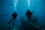 two divers hovering above an underwater wreck